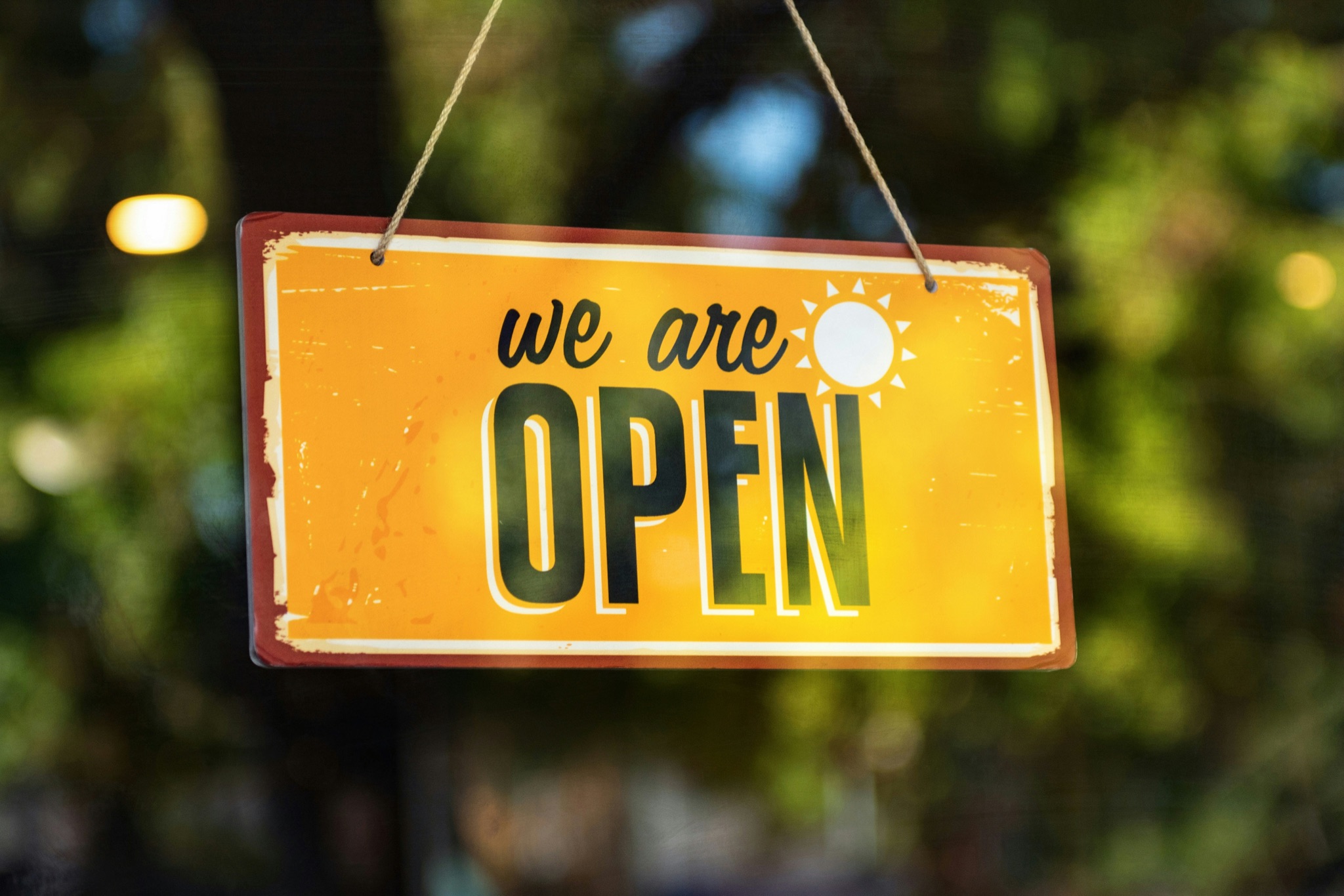 A bright we are open sign hanging in a shop window